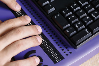 Purple Keyboard with brail buttons and a hand typing.