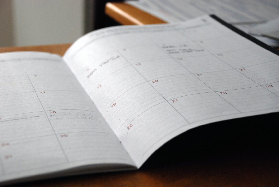 An open calendar book sitting on a desk.